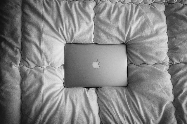 Macbook položený na veľkom paplóne na posteli.jpg